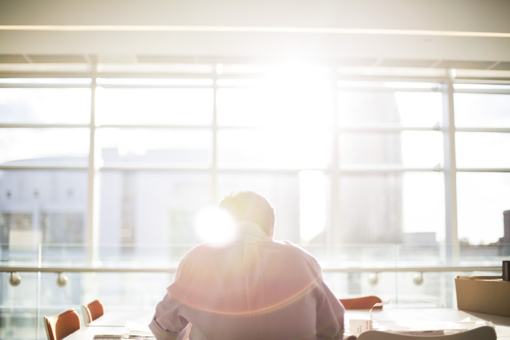  A man working while sitting in front of a window during daytime