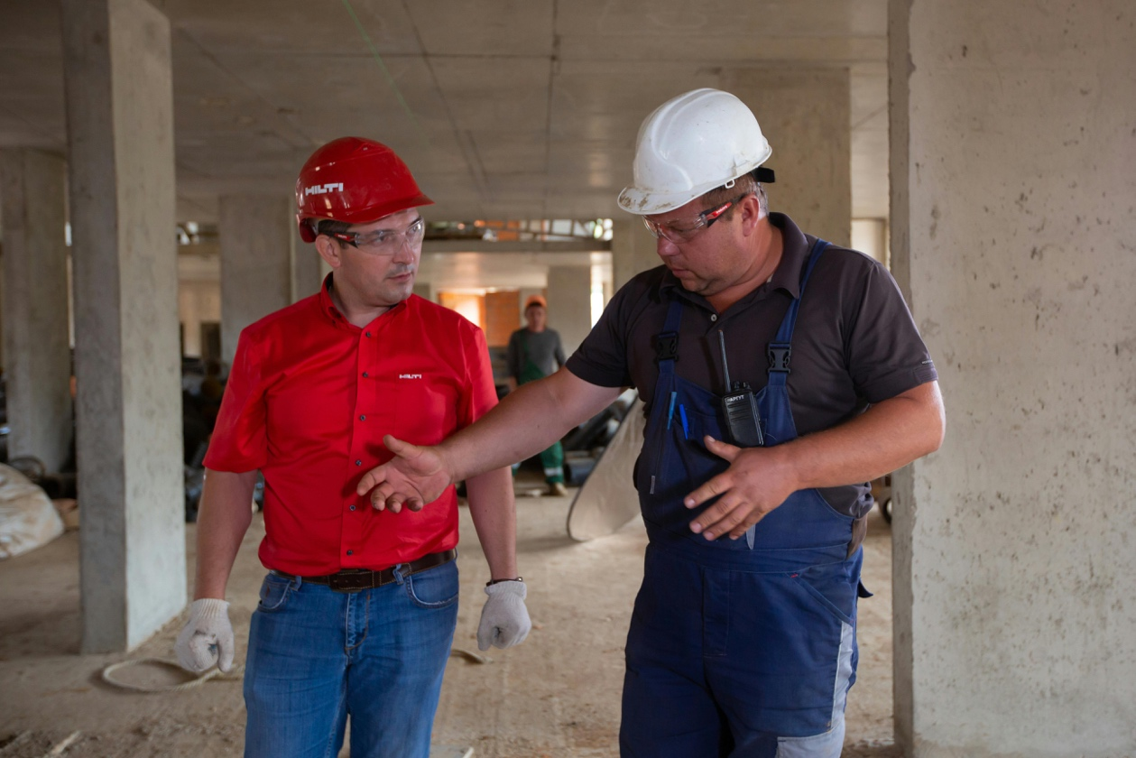 Two men wearing safety helmets talking at a construction site 