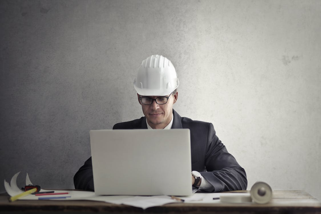  A man in a hard hat working with a laptop at a table