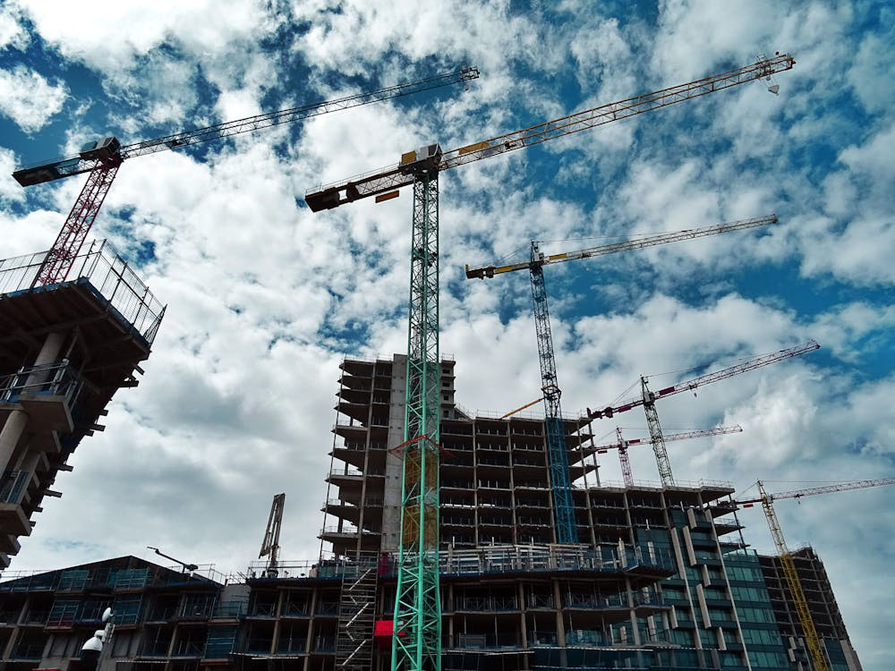 Green and yellow cranes at a construction site