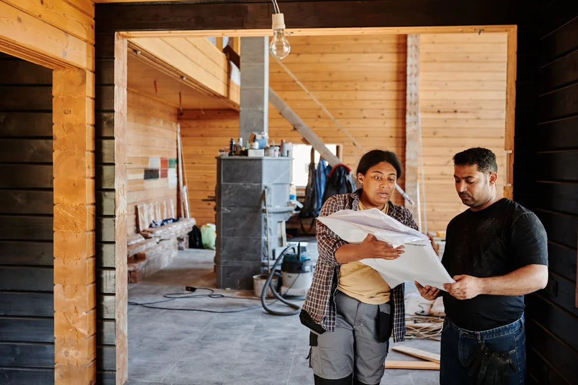 An image of two people looking at a blueprint at a construction site  