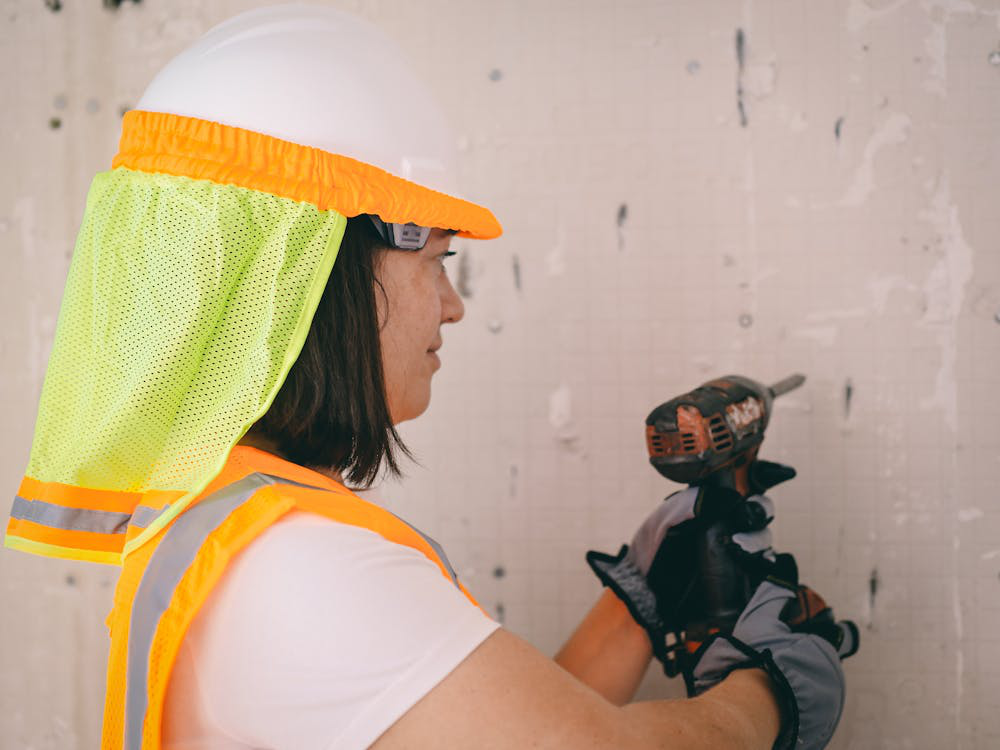 An image of a woman using a drill on the wall  