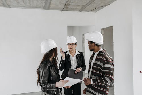 Three people at a construction building analyzing construction delay issues