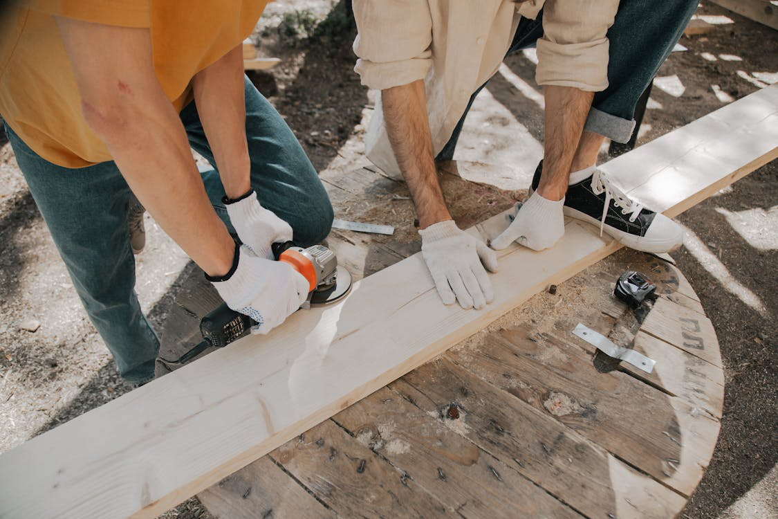 An image of a person using a grinder on a wood plank   
