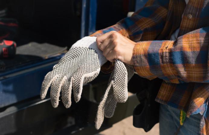 A person wearing protective gloves on a worksite.