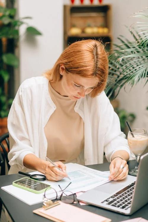  A woman sitting at a desk with coffee and a smartphone.