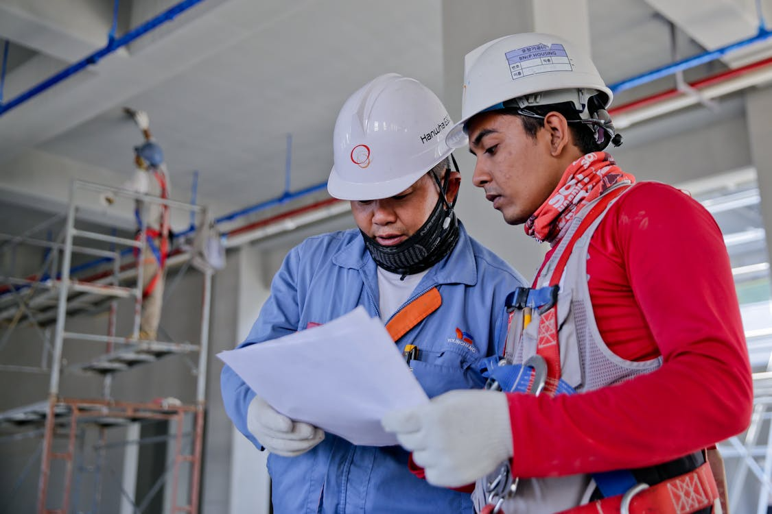 Two people wearing PPE and reviewing a paper