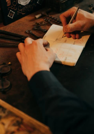 A person writing on white paper with a pen.