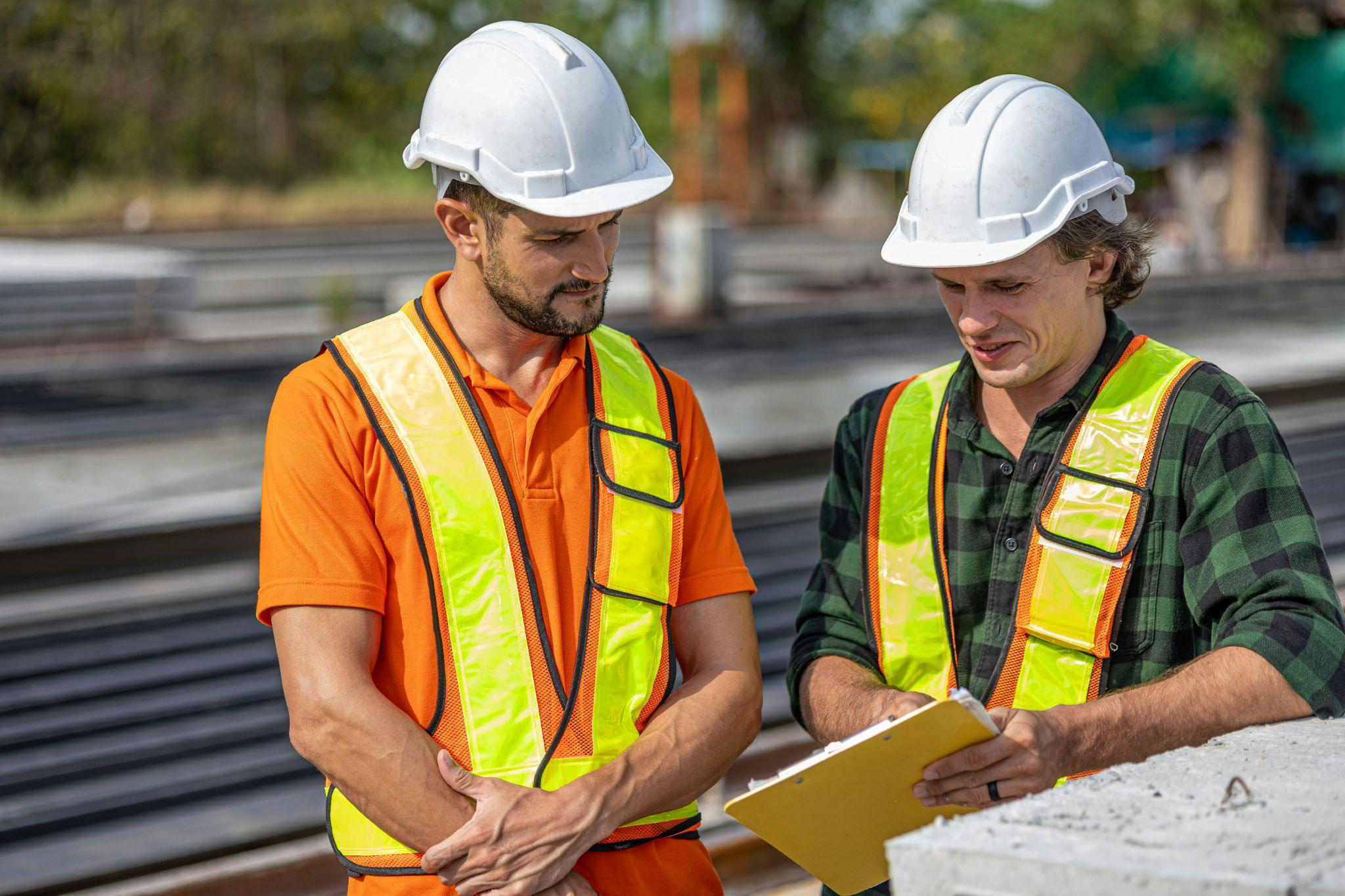 two construction workers in uniform discussing a document