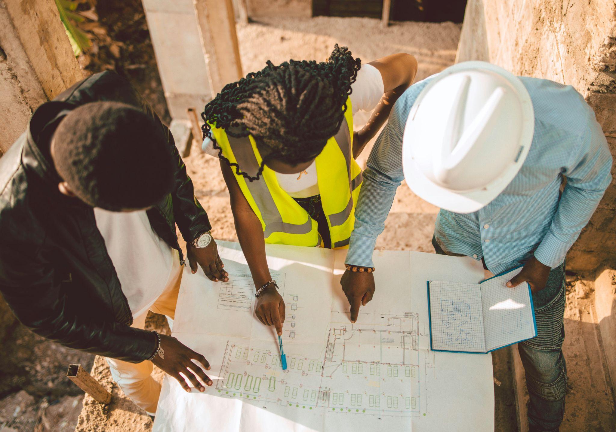three construction workers discussing construction plans on a sheet