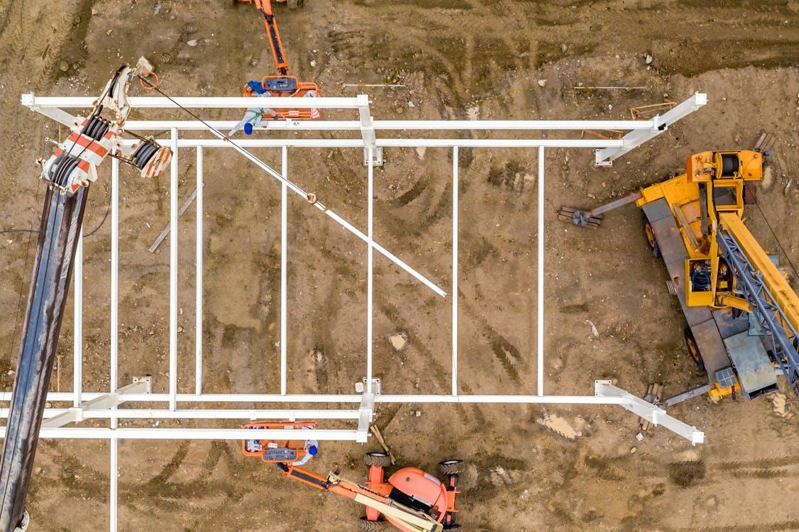 Aerial view of construction site showing structural framework and heavy equipment in operation.