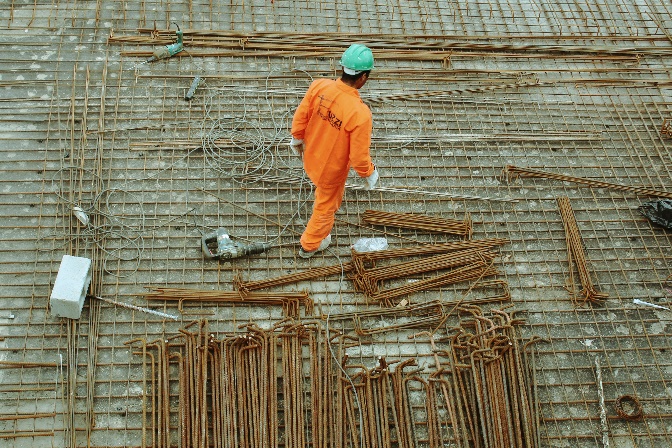 Construction worker walking across reinforced concrete and rebar during foundation work, representing the project documentation and field evidence used in construction delay dispute resolution.
