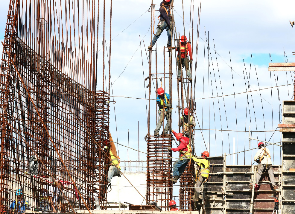 Construction workers assembling reinforced concrete structures on scaffolding, highlighting the field operations often examined during construction delay claim investigations.